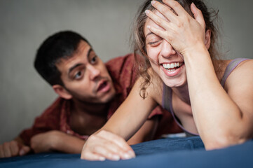 Fototapeta na wymiar A man and a woman are arguing on the bed in the apartment. They are in a bad mood because they have love problems.