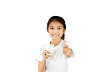 A young Asian girl in a white T-shirt is smiling. His right hand holds a glass of milk and his left hand thumbs up isolated on a white background with clipping path.