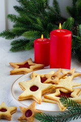 Star-shaped cookies, Christmas tree branches and candles on the table