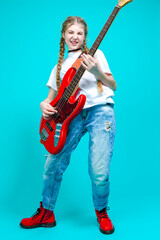 Caucasian Teenager Guitar Player With Red Shiny Bass Guitar Posing In Casual White Shirt Showing Pleased Expression On Turquoise Background.