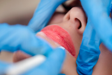 Fototapeta premium Young woman undergoing procedure of permanent lip makeup in tattoo salon, closeup