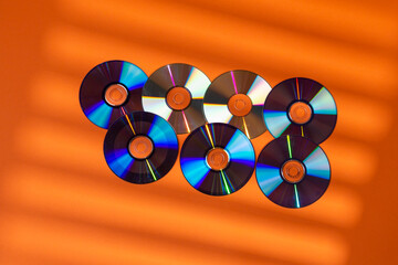 Large Variety of Arranged CD Disks or DVD Disks on Orange Background With Different Patterns or...