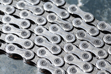 Upper Closeup View of Shiny Dirty Greasy Oiled Bicycle Chain As A Part of Metal Bicycle Equipment On Grey Tile Stony Background With Contrast Details