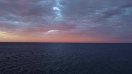 Flying above the sea at sunset with colorful clouds orange