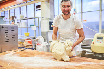 Baker apprentice kneads dough in preparation for baking bread