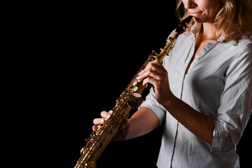 Obraz premium soprano saxophone in the hands of a girl on a black background
