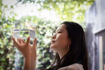 Creative female designer looking at cube with water at window