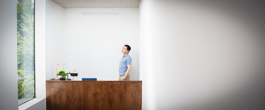 Thoughtful male engineer standing behind desk in office