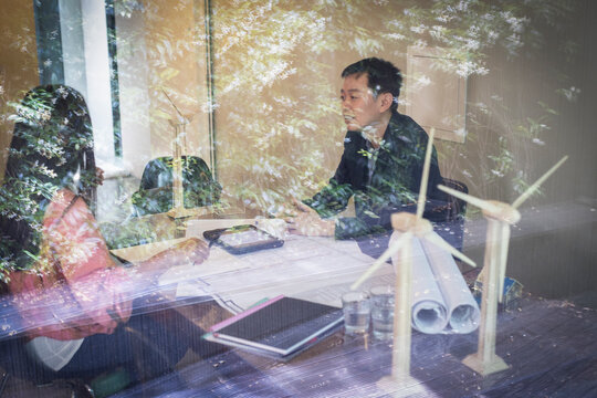 Engineers with wind turbine models meeting in office