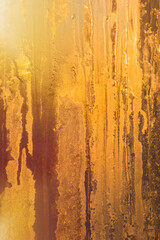 Frosty patterns on the glass, the dawn sun through the frost, yellow vertical abstract winter background