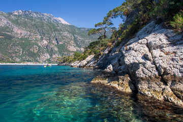 Beautiful landscape on the sea, the rocky coast, view on the mountains and small boat with people. Blue lagoon in Oludeniz, Turkey. Small boats on clear water.  Tourism.