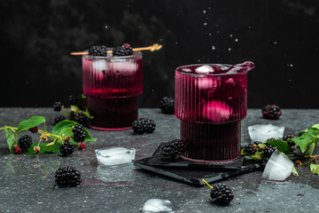 Blackberry lemonade or mojito. Refreshing lemonade with blackberry and ice on a dark background....