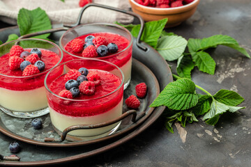 Raspberry Panna cotta with raspberry jelly on a dark background. Berry dessert with cream sauce in...