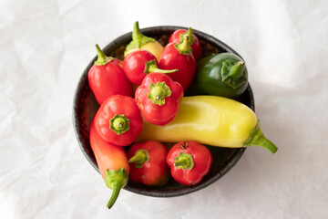 Red hot peppers, green hot peppers and yellow hot peppers in a bowl.