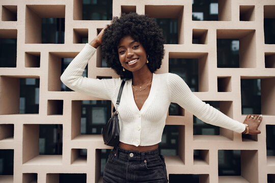Stylish pretty african woman with hairstyle posing near geometric wall