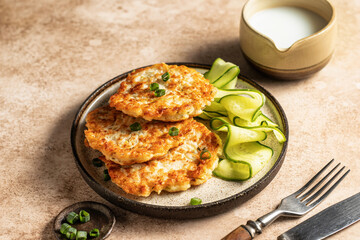 Vegetarian zucchini pancakes served with cucumber and cream sauce on brown background with cutlery