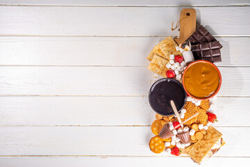 S'mores home party food and ingredients. Smores buffet background with various marshmallow, crackers, chocolate, fruits, chocolate, toppings, sauces. Traditional autumn summer american smores dessert