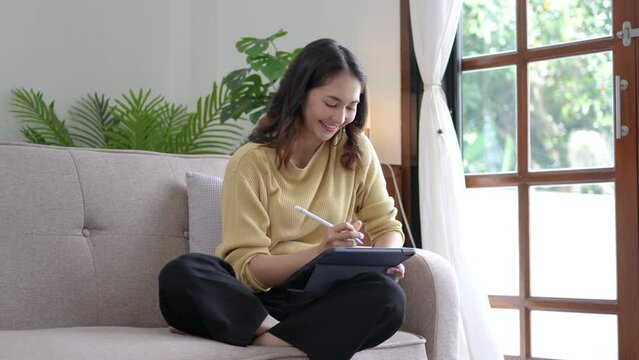 Young Asian woman using tablet at home.