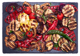 Grilled vegetables mix on a stone serving board - zucchini eggplant onions corn mushroom tomato