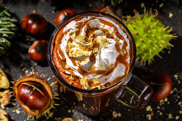 Glass cup with dark chestnut hot chocolate or choco latte, with whipped cream, caramel sauce and...