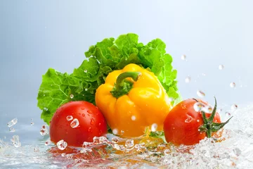 Foto op Plexiglas fresh vegetables in splashing water on blue background. © zhane luk