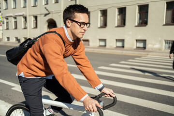 A cyclist goes to work with a briefcase. Urban ecotransport.  Fitness watch on hand.