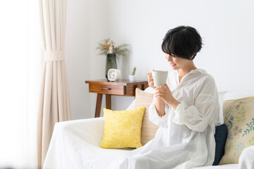 Woman relaxing with a cup of coffee in her room, profile.