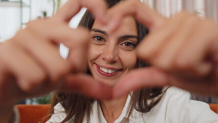 I love you. Adult girl makes symbol of love, showing heart sign to camera, express romantic feelings, express sincere positive feelings. Charity, gratitude, donation. Young woman close-up happy face