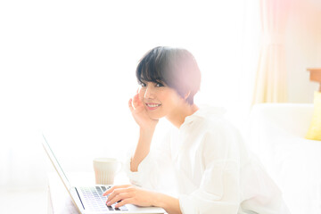 コピースペースが使いやすい綺麗な逆光の中仕事をする女性　ピンクの前ボケあり　カメラ目線