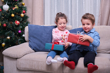 Little boy and girl exchanging Christmas presents, children enjoying Christmas gifts