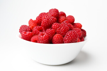 Fresh raspberries in the white bowl on the white background. Fresh raspberries isolated on white. Healthy eating