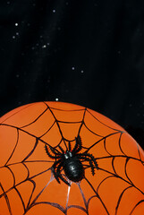 Halloween decor - black spider and cobwebs on a solid orange background.
