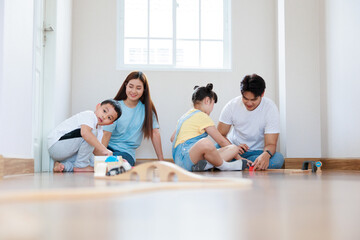 Fototapeta premium Happy asian family playing wood block create rail road together at home