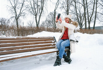 A young woman takes a selfie on a smartphone with winter skates. Virtual communication on the...