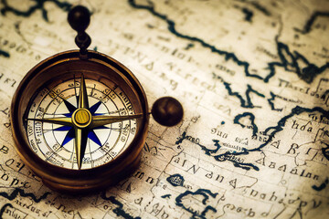Fototapeta na wymiar Vintage navigation compass isolated on an old geographical map of the world, history of geography and humanities exploration
