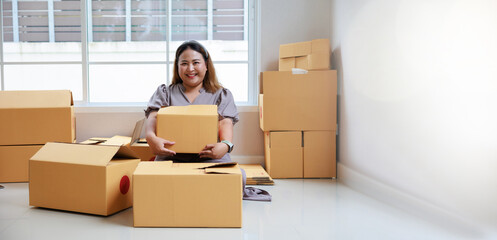 Fototapeta na wymiar Asian woman startup packaging business, holding parcel box, order by online at her home.