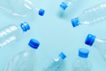 Plastic used bottles on a blue background. There is empty space in the center. The concept of consumerism and pollution of nature with plastic waste. Selective focus on background
