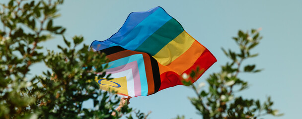 person flies a progress pride flag, web banner
