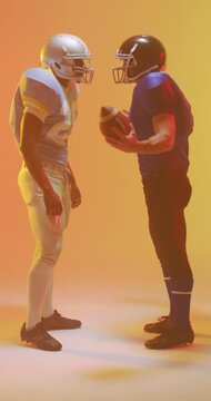 Vertical video of diverse male american football players with neon orange lighting