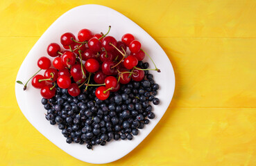 cherries and blueberries on a plate, summer seasonal berries rich in vitamins for proper nutrition