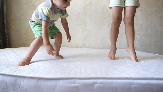 Close up of two little children, brother and sister, jumping on mattress. Cheerful active kids having fun playing during the repair.Leisure activity, lot of energy, hyperactive kid concept.Childhood.