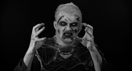 Portrait of sinister man in carnival costume of Halloween crazy zombie with bloody wounded scars...