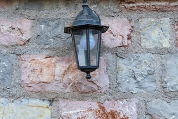 an old street lamp attached to the stone wall of an old building. Old lighting fixtures. An antique lamp.
