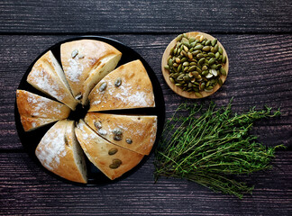 Pumpkin bread with pumpkin seeds and thyme on wooden background, top view 