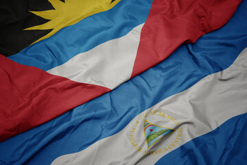 waving colorful flag of antigua and barbuda and national flag of nicaragua. 3d illustration