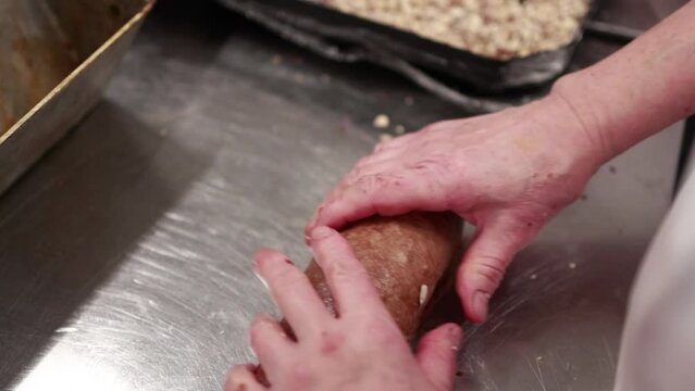 baker kneading dough and rolls the dough in seeds and sesame seeds before baking bread