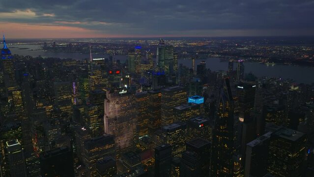 Aerial panoramic footage of downtown high rise buildings in large city at twilight. Lighted windows and colourful rooftops of skyscrapers. Manhattan, New York City, USA