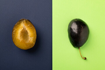 Sliced ​​ripe plum on a bright abstract background. Flat composition.