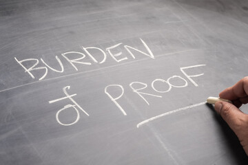 Fototapeta premium Closeup hand write the text Burden of Proof, on the blackboard, topic of law learning concept
