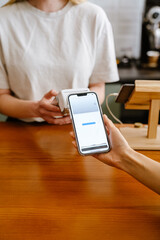 Blonde white barista woman working with terminal in cafe